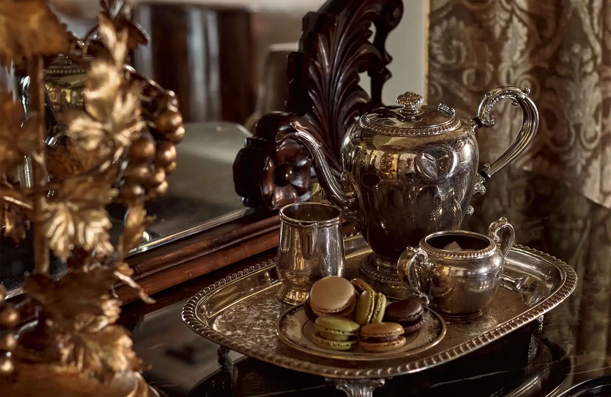 closeup of silver tea set and plate of macarons