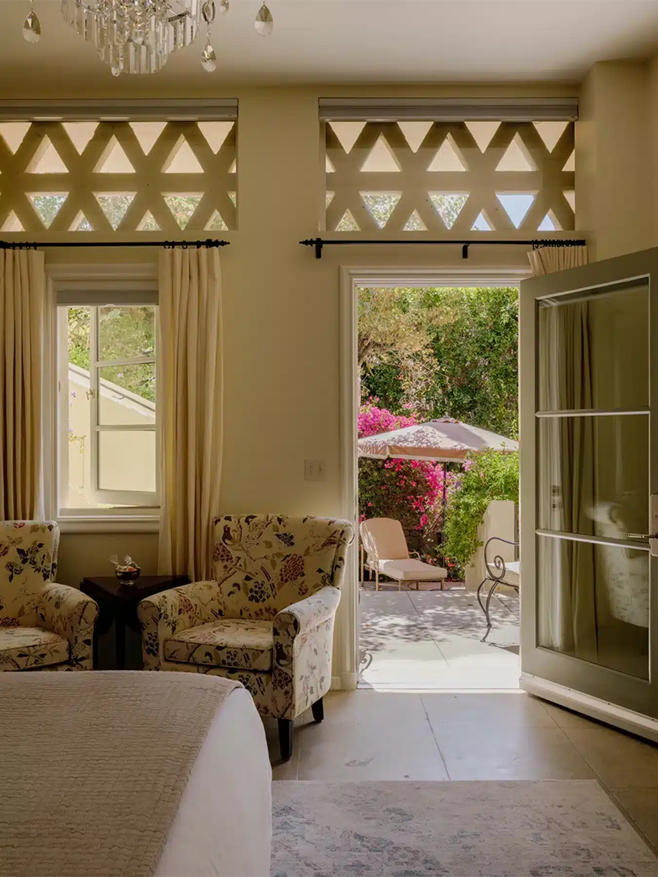 Orchid Tree room with bed and two sitting chairs, with door open leading to patio seating