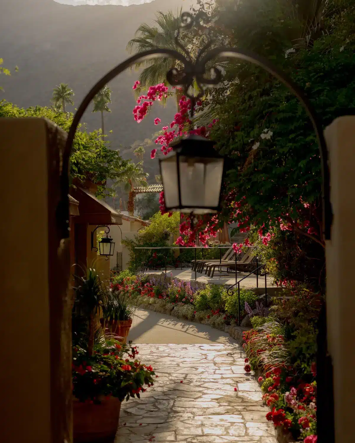 Gate and lantern light over walkway leading to patio and garden